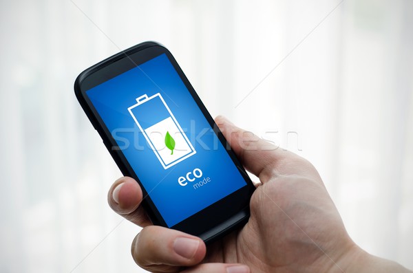 Man holding phone with eco battery mode on display Stock photo © simpson33
