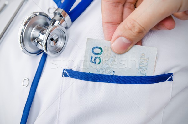 Patient bribing doctor, puts money into the pockets Stock photo © simpson33