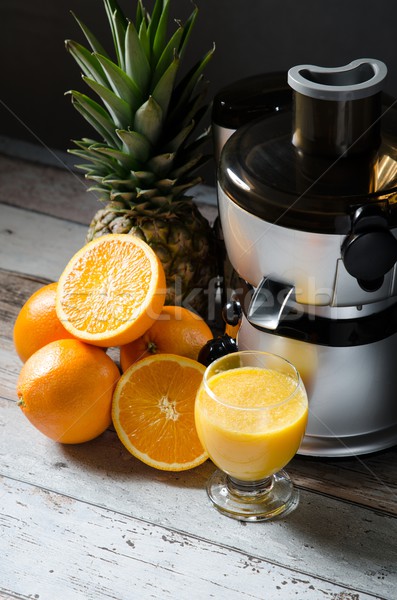 Juicer and orange juice in glass on wooden desk Stock photo © simpson33