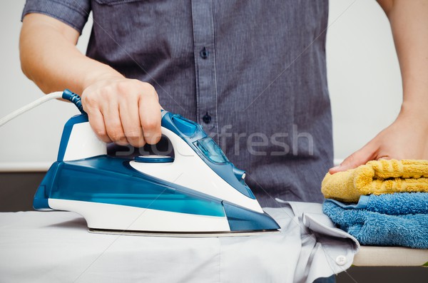 Man irons clothes on ironing board with blue iron Stock photo © simpson33