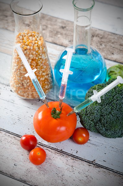 Syringe in tomato. Genetically modified food concept on wooden b Stock photo © simpson33