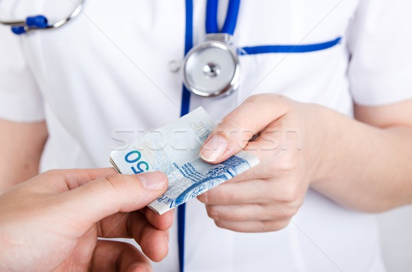 Patient bribing doctor, giving money to the hand Stock photo © simpson33