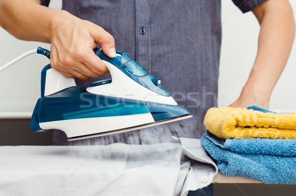 Man irons clothes on ironing board with steaming iron Stock photo © simpson33