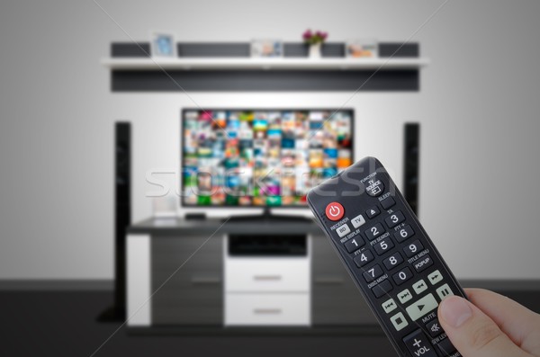 Watching television in modern TV room. Hand holding remote Stock photo © simpson33