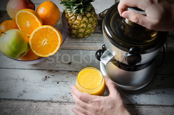 Man preparing fresh orange juice. Fruits in background Stock photo © simpson33