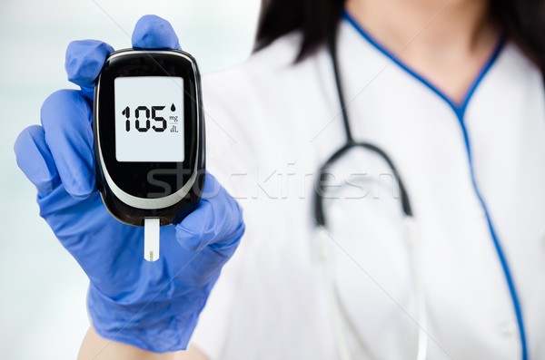 Stock photo: Closeup composition of woman doctor holding glucometer. 