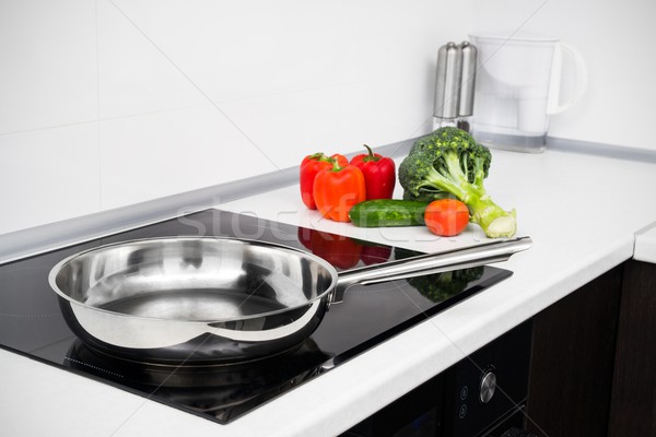 Frying pan and vegetables in modern with induction stove Stock photo © simpson33