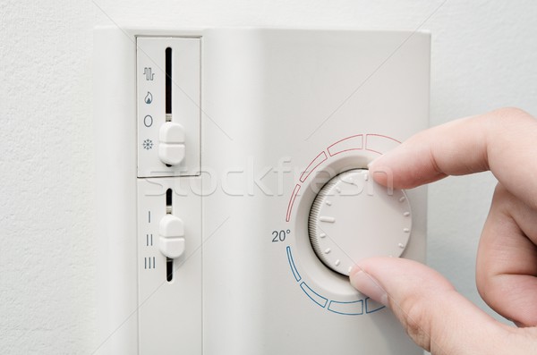Hand switches air conditioner thermostat on wall Stock photo © simpson33