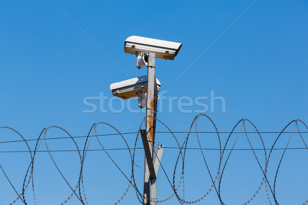 Foto d'archivio: Filo · spinato · recinzione · telecamera · di · sicurezza · cielo · blu · sicurezza