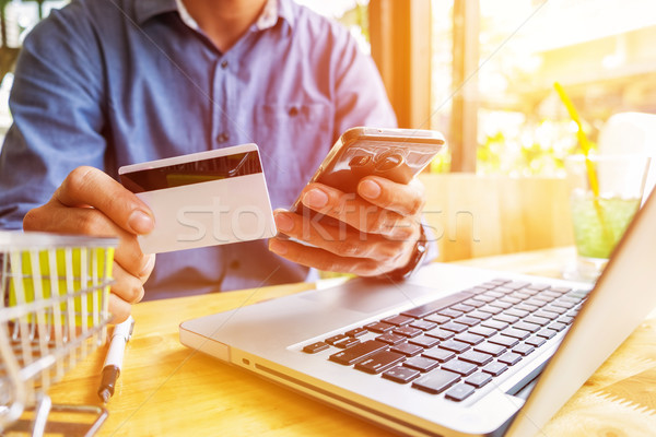 Stock photo: Man holding credit card in hand and entering security code using