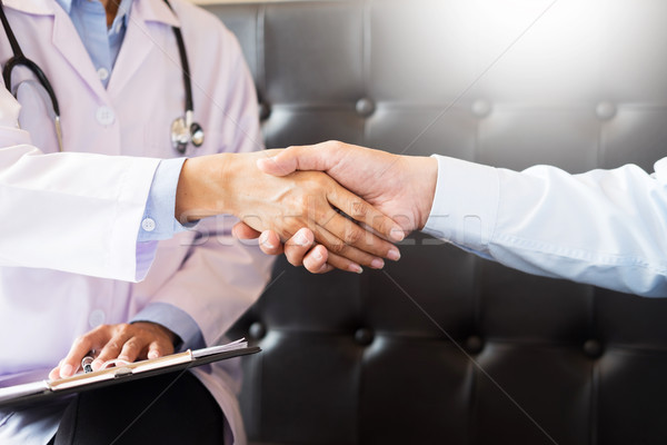 Doctor shakes hands at medical office with patient, wearing glas Stock photo © snowing