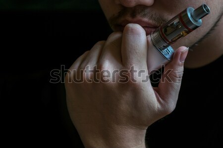 Stock photo: Man with concealed identity smoking a controversial vaping an el