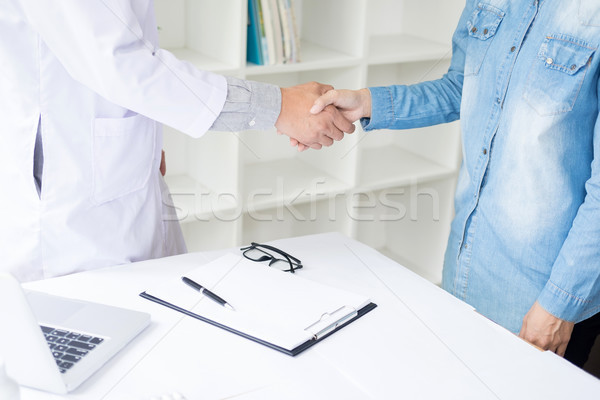 Doctor shakes hands at medical office with patient, wearing glas Stock photo © snowing
