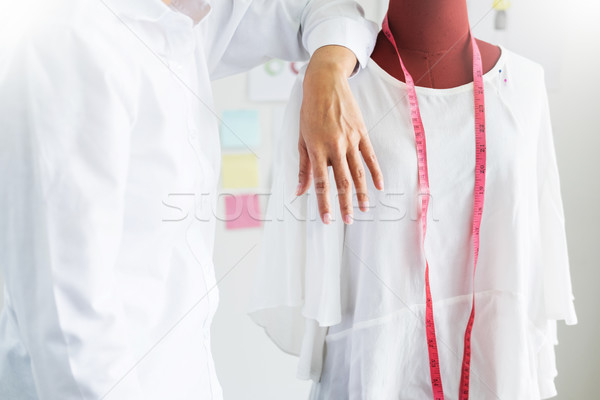 Stock photo: Asian tailor adjusts garment design on mannequin in workshop mak