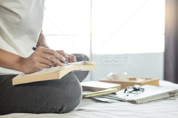 Young woman sitting working and writing in the notebook on bed l Stock photo © snowing