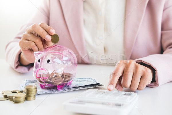 Close up of Businessman putting coin into small piggy bank , The Stock photo © snowing