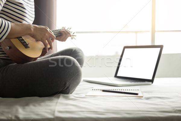 Happy young asian woman playing ukulele sitting on bed in bedroo Stock photo © snowing