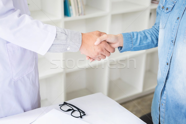 Doctor shakes hands at medical office with patient, wearing glas Stock photo © snowing