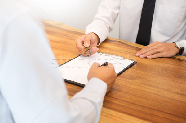 Estate agent in suit sitting in an office desk Handing over of h Stock photo © snowing