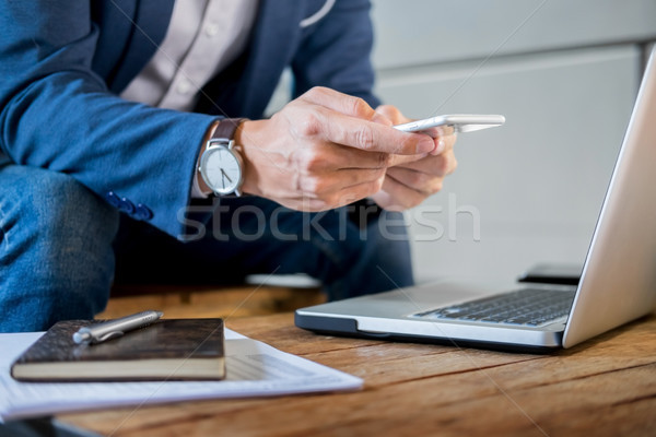 Stock photo: Young successful businessman typing a text on mobile phone. whil