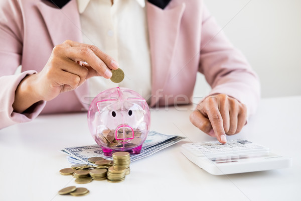 Close up of Businessman putting coin into small piggy bank , The Stock photo © snowing