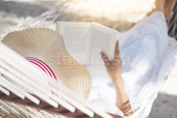 Young lady reading a book in hammock on tropical sandy beach. Stock photo © snowing