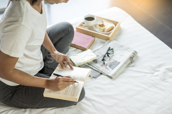 Young woman sitting working and writing in the notebook on bed l Stock photo © snowing