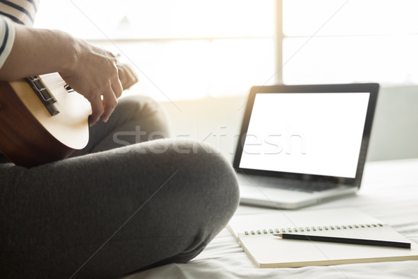 Happy young asian woman playing ukulele sitting on bed in bedroo Stock photo © snowing