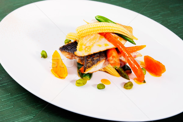Pan seared sea bass served with stir fried baby vegetables Stock photo © SophieJames