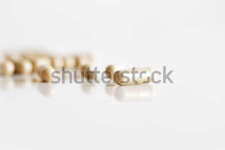 A handful of capsule tablets on white reflective ceramic surface Stock photo © SophieJames