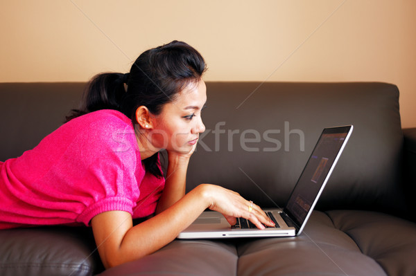 Young woman laying on a couch and using a laptop Stock photo © SophieJames