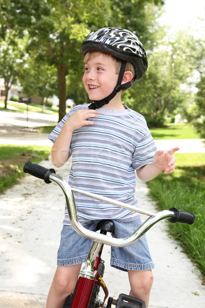 A close up of a young boy who is getting ready to go on a bike ride. He is adjusting his helmet Stock photo © soupstock