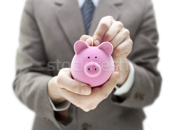 Stock photo: Businessman putting coin into the piggy bank