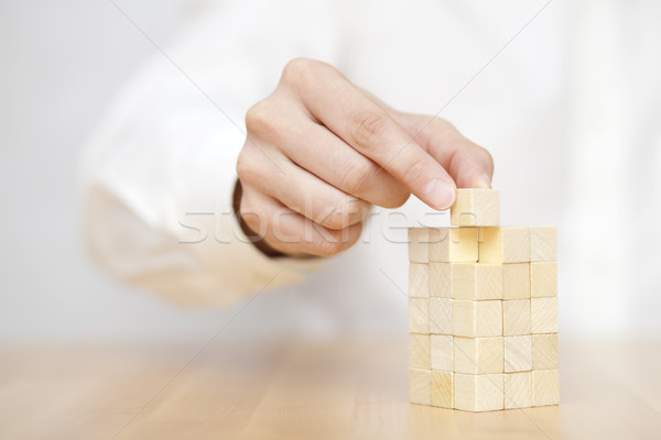 Man's hand adding the last missing wooden block into place. Business success concept.  Stock photo © sqback