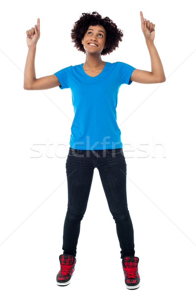 Amused young lady pointing and looking upwards Stock photo © stockyimages