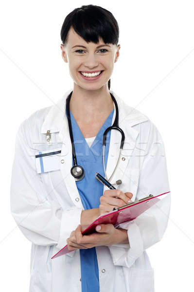 Friendly doctor updating medical record of a patient Stock photo © stockyimages
