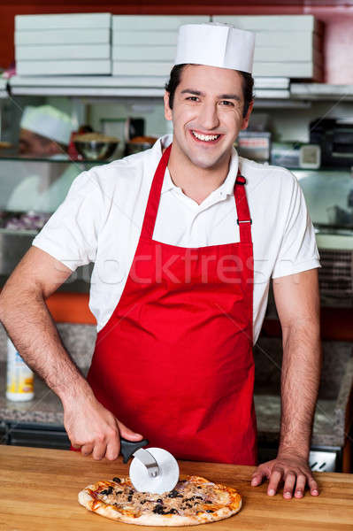 Smiling chef cutting pizza with cutter Stock photo © stockyimages