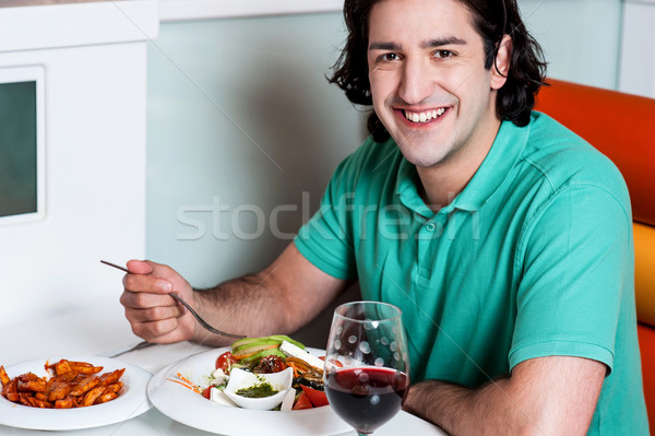 Young smiling man eating at restaurant Stock photo © stockyimages