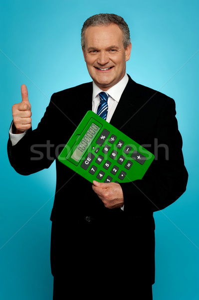 Businessman showing thumbs up, holding calculator Stock photo © stockyimages