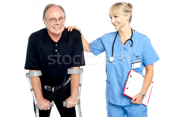 Cheerful doctor encouraging her patient to walk with crutches Stock photo © stockyimages