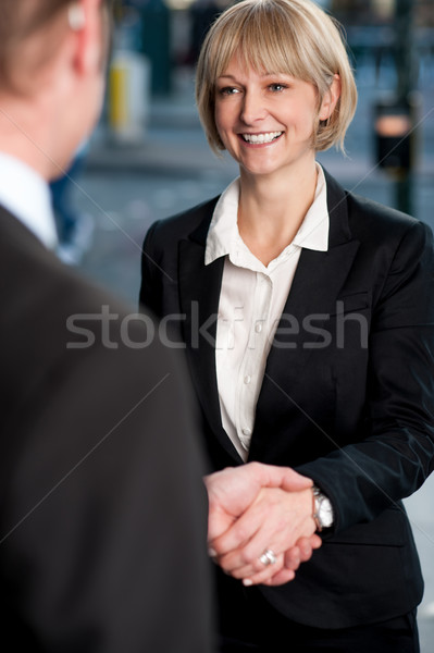 Two corporate identities shaking hands Stock photo © stockyimages
