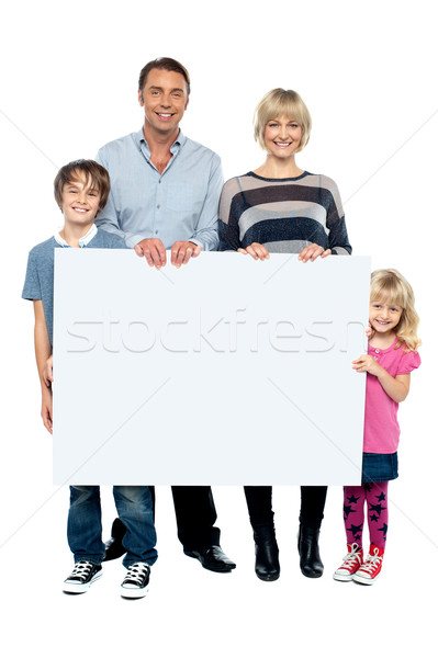 Active young family displaying blank ad board Stock photo © stockyimages