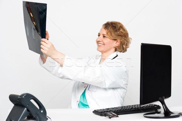 Stock photo: Smiling female surgeon looking at patients x-ray