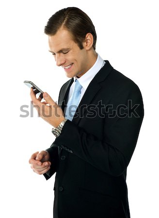 Male executive smiling as he reads message on his mobile Stock photo © stockyimages