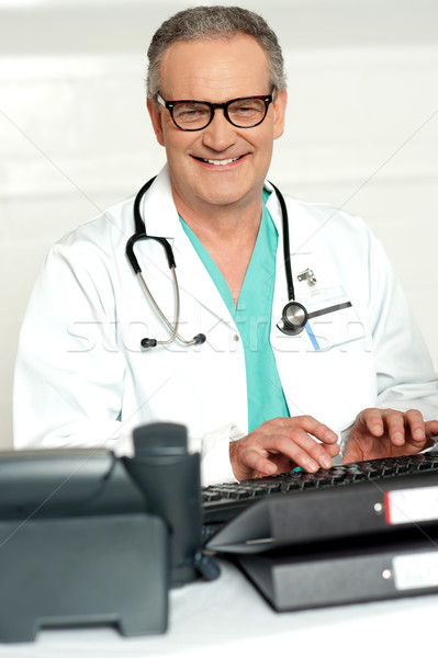 Smiling physician in eye wear typing on keyboard Stock photo © stockyimages