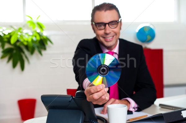 Bespectacled boss presenting a compact disk Stock photo © stockyimages