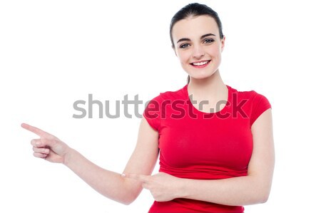 Smiling young woman pointing to her right Stock photo © stockyimages
