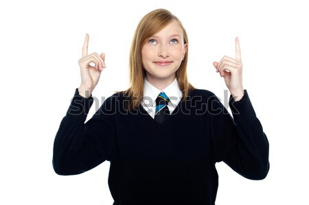 Amused schoolgirl looking and pointing upwards Stock photo © stockyimages