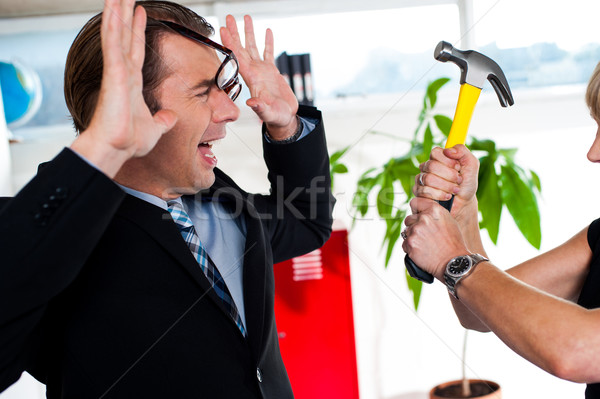 Woman threatening her boss, holding hammer. Stock photo © stockyimages