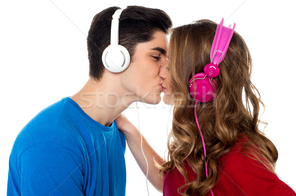 Young couple enjoying music and kissing Stock photo © stockyimages